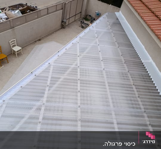 גג פלסטיק שקוף מותקן על מבנה עם כיסאות ופסולת ברקע